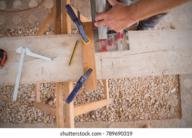 Carpenter Using Electrical Saw On Raw Wood In His Garage.