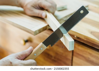 carpenter using Japanese saw or pull saw ,Crosscutting on wood on table, DIY maker and woodworking concept. selective focus - Shutterstock ID 2150002355
