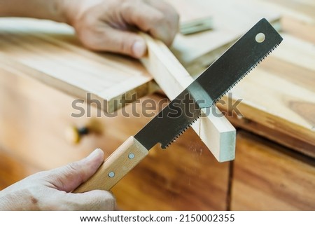 carpenter using Japanese saw or pull saw ,Crosscutting on wood on table, DIY maker and woodworking concept. selective focus