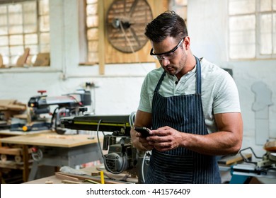 Zimmermann mit Telefon in seiner Werkstatt