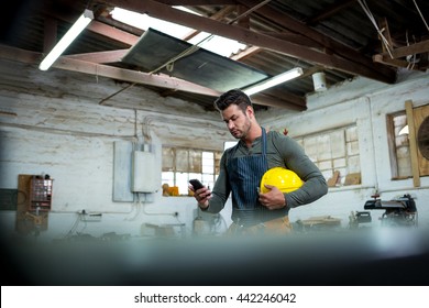 Carpenter Using Phone On His Workshop