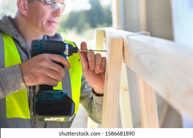 Carpenter Using Power Drill To Screw Wood Frame Together On Construction Site Interior