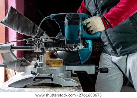 Carpenter using professional circular saw with a miter in the woodcraft carpentry workshop. 