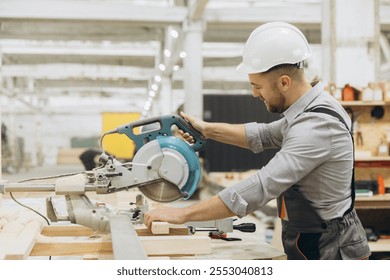 Carpenter wearing safety helmet using circular saw cutting wooden plank in a modern and bright woodwork carpentry - Powered by Shutterstock