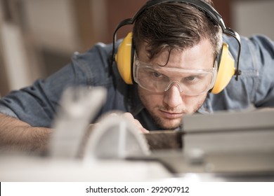 Carpenter while using electric tools wearing protective headphones - Powered by Shutterstock