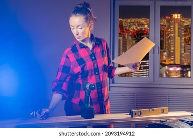 Carpenter Woman. Portrait Of Carpenter At Work. She Draws With Pencil On Blackboard. Girl Carpenter With Drawings. Girl In Home Workshop With Window. Concept - She Is Furniture Maker.