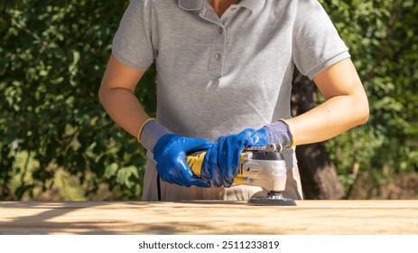 Carpenter Woman Wearing Protective Gloves Using Power Sander For Sanding Wooden Plank Outdoors. Concept Of Reconstruction And Restoration Of Wooden  - Powered by Shutterstock