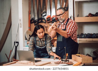 Carpenter woodwork factory owner and partner working in wood workshop with blueprint and laptop discussing about home furnishing design project. - Powered by Shutterstock