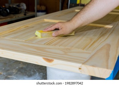 Carpenter in work on worker sanding with sanding block wooden interior doors