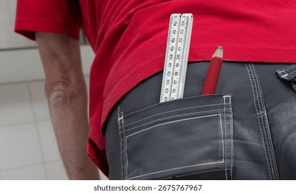 Carpenter at work outdoors on a  constructionsite. Craftsman at work climbing on a ladder with folding ruler in his back pocket