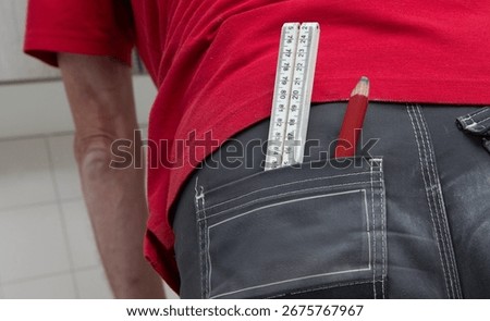 Carpenter at work outdoors on a  constructionsite. Craftsman at work climbing on a ladder with folding ruler in his back pocket