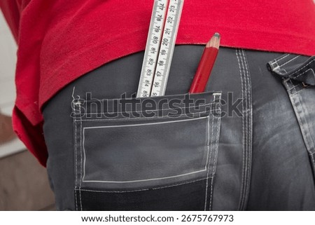 Carpenter at work outdoors on a  constructionsite. Craftsman at work climbing on a ladder with folding ruler in his back pocket