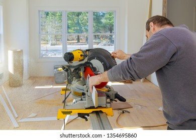 Carpenter at work using circular saw cutting wood moldings baseboard