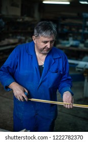 Carpenter at work in workshop, a man makes measurements