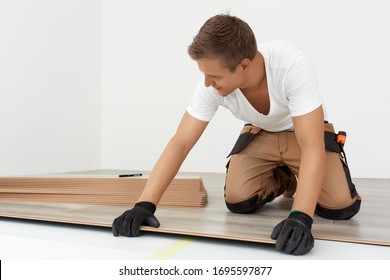 Tischlerarbeiter, der Laminatfußböden im Zimmer installiert. Aufbau eines schwimmenden Fußbodens - Fußbodenbelag - Laminat