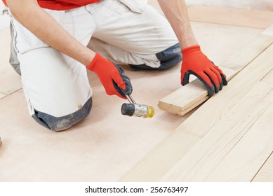 Carpenter Worker Installing Wood Parquet Board During Flooring Work With Hammer