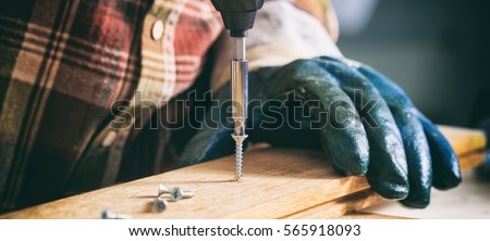 Carpenter working with an electric screwdriver on the work bench