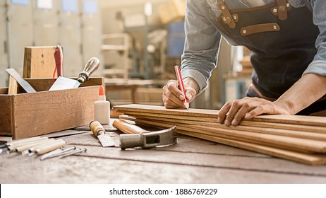 Tischler, der mit der Ausrüstung auf Holztisch in der Tischlerei arbeitet. Frau arbeitet in einer Tischlerei.