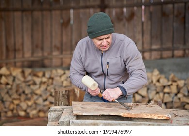 Carpenter working with hammer and chisel on a walnut wood
