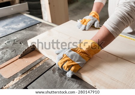 Carpenter working with Industrial tool in wood factory, circular blade with a wood board