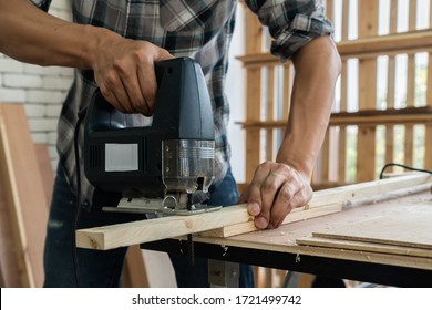 Carpenter working on wood craft at workshop to produce construction material or wooden furniture. The young Asian carpenter use professional tools for crafting. DIY maker and carpentry work concept. - Shutterstock ID 1721499742
