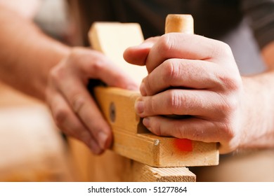 Carpenter working with a planer in his workshop, close up on the tool with hands