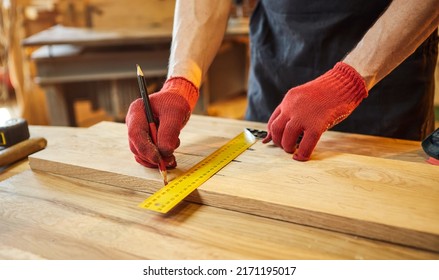 Carpenter working with a wood, marking plank with a pencil and taking measurements to cut a piece of wood to make a piece of furniture in a carpentry workshop, close-up view - Shutterstock ID 2171195017