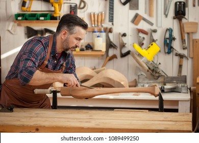 Carpenter Works With A Planer In A Workshop For The Production Of Vintage Furniture. He Makes Cabriole Leg For A Table In The Style Of Louis XV And Queen Anne/Joiner Makes Cabriole Leg For Vintage Tab