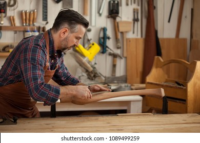 Carpenter Works With A Planer In A Workshop For The Production Of Vintage Furniture. He Makes Cabriole Leg For A Table In The Style Of Louis XV And Queen Anne/Joiner Makes Cabriole Leg For Vintage Tab