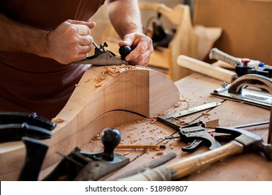 Carpenter works with a planer in a workshop for the production of vintage furniture. He makes cabriole leg for a table in the style of Louis and Queen Anne/Joiner Makes Cabriole Leg for Vintage Table - Powered by Shutterstock