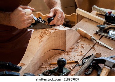 Carpenter Works With A Planer In A Workshop For The Production Of Vintage Furniture. He Makes Cabriole Leg For A Table In The Style Of Louis And Queen Anne/Joiner Makes Cabriole Leg For Vintage Table