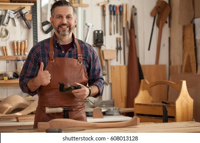 Carpenter Works With A Planer In A Workshop For The Production Of Vintage Furniture. He Makes Cabriole Leg For A Table In The Style Of Louis And Queen Anne/Joiner Makes Cabriole Leg For Vintage Table