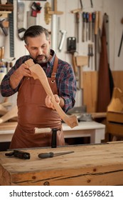 Carpenter Works With A Planer In A Workshop For The Production Of Vintage Furniture. He Makes Cabriole Leg For A Table In The Style Of Louis XV And Queen Anne/Exquisite Lines Of The Cabriole's Legs