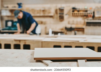 Carpenter works with wood in carpentry workshop. Man doing woodwork professionally - Powered by Shutterstock