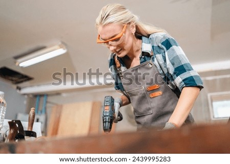 In the carpenter's shop, a professional woman crafts wooden furniture, using tools with skill in her woodwork occupation, showcasing industry prowess.