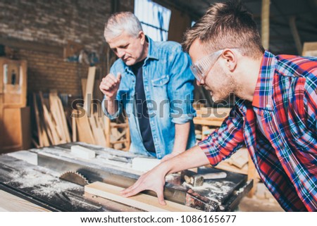 Carpenters using circular saw in workshop