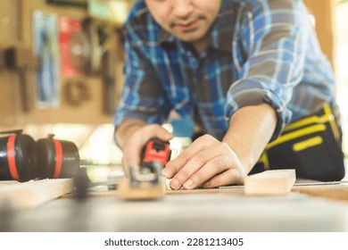 Carpentry professional, hand of asian young man, male carpenter use tape measure, tool on board wood in small shop. Woodwork, furniture making, construction industry. Owner small business people.