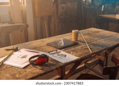 A carpentry shop setup for work with materials, designs and tools on the table with no one inside.