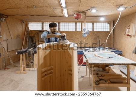 Carpentry studio worker using grinding machine for finishing wood construction