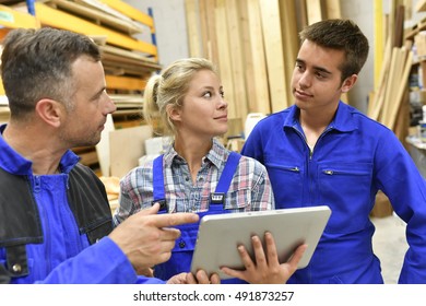 Carpentry teacher using tablet to train apprentice