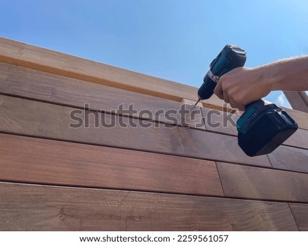 Carpentry worker building wooden deck siding boards close up