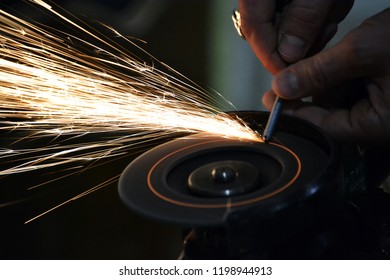 Carpentry workshop. Repairs. Work with the grinder. Grinding wheel. Hardware. Sparks. Hands of the master close up. Glowing circle. Industrial photo.
 - Powered by Shutterstock