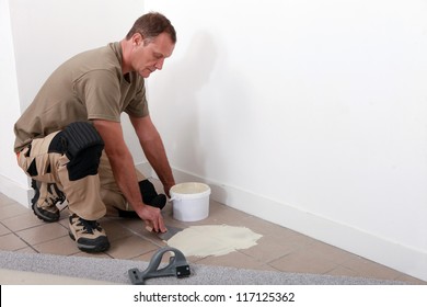 Carpet Fitter Applying Adhesive Over An Old Tiled Floor