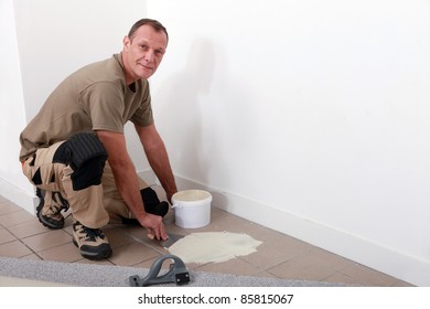 Carpet Fitter Spreading Adhesive On A Tiled Floor