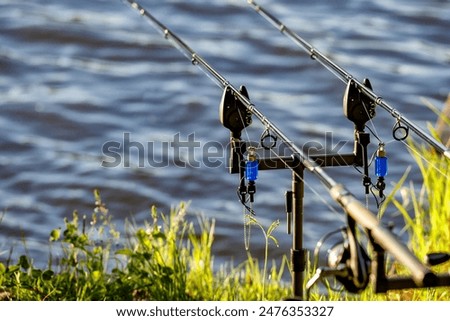 Carpfishing session at the Lake.Carp fishing rods standing on special tripods.Scenic landscape overlooking lake at Dawn.Fishing adventures, carp fishing.