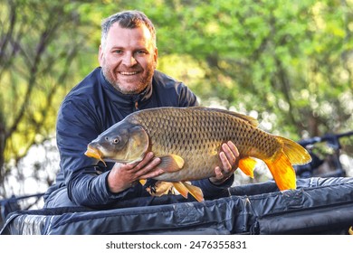 Carpfishing session at the Lake.lucky fisherman holding a giant common carp.Angler with a big carp fishing trophy.Fishing adventures.Fish trophy - Powered by Shutterstock