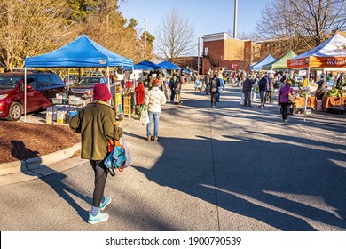 Carrboro, North Carolina USA-01 23 2021: An Older Woman Brings Shopping Bags To The Carrboro Farmers Market And Others Shop For Food.