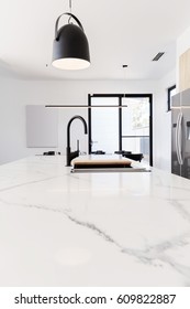 Carrera marble benchtop with black goose neck kitchen tap and black pendant light