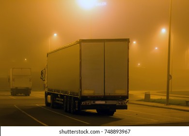 Carriage Of Goods By Road, Trucking Industry - Semi-trailer Truck, Overweight Vehicle, Large Goods Vehicle In Parking Lot, In Night Fog, Foggy Road