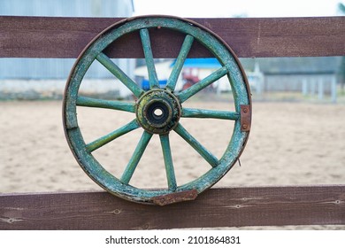 The carriage wheel hangs on the fence.